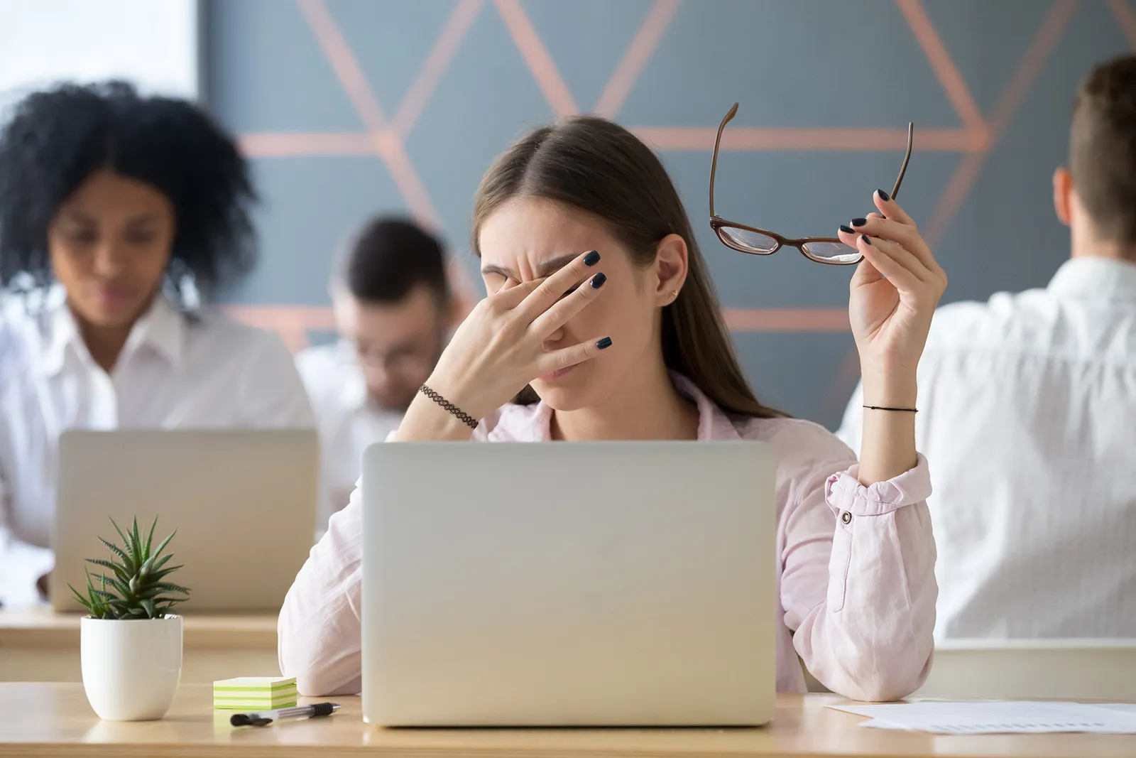 A woman rubbing tired eyes at her laptop