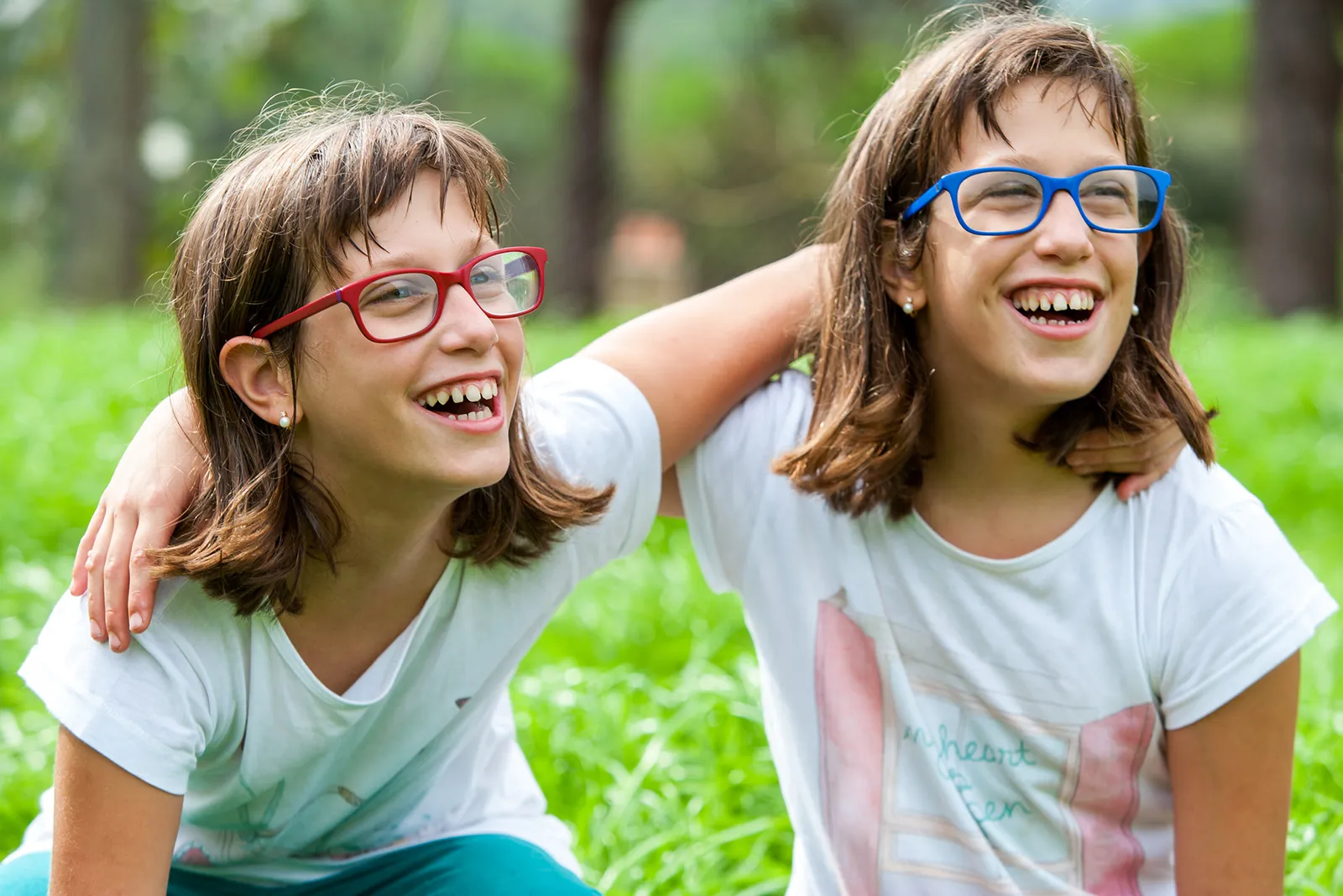 Two smiling girls wearing red and blue frames