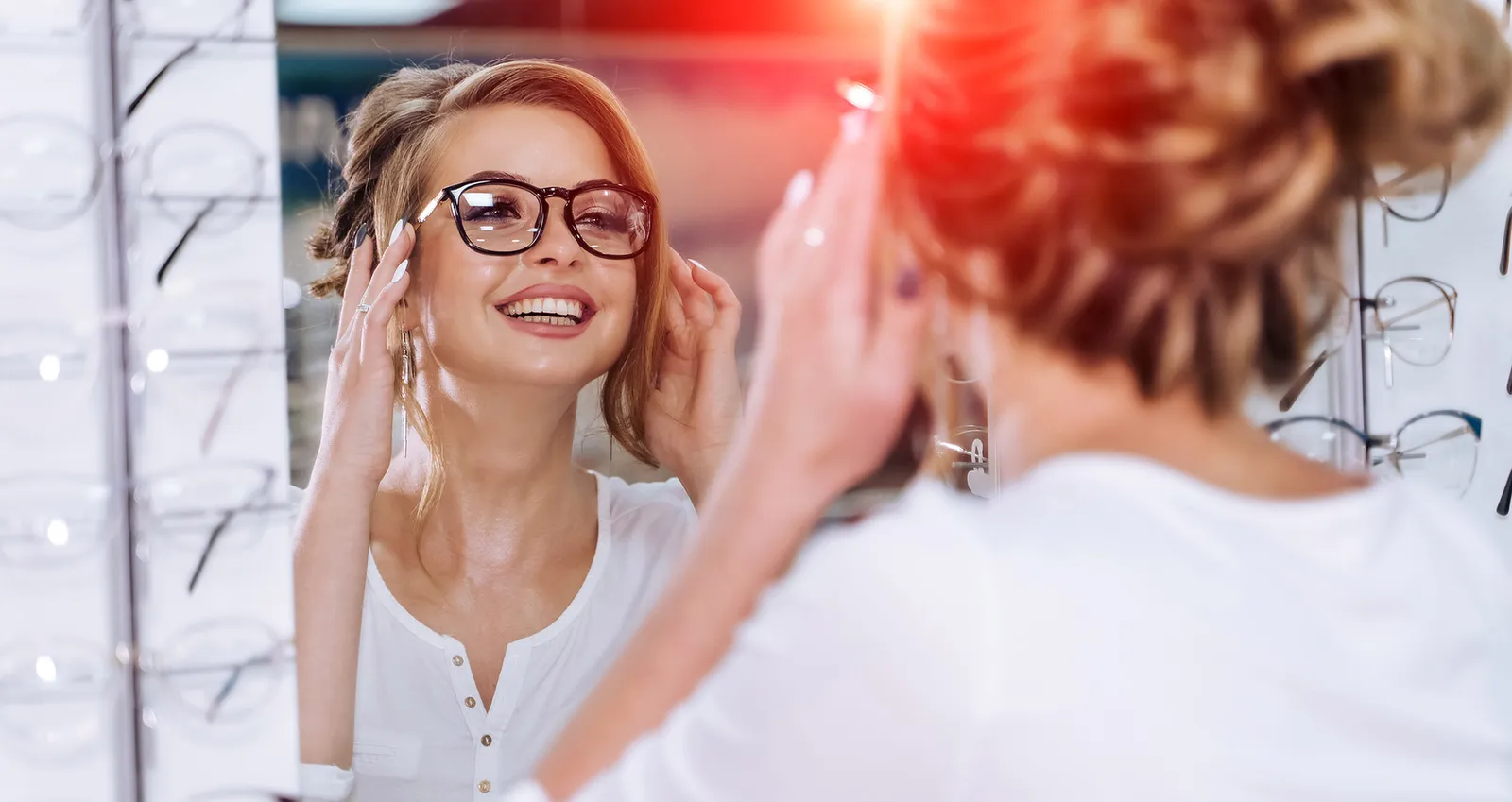 A woman trying on a new pair of glasses with help from an optician
